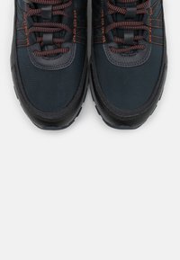 Botas de senderismo negras y marinas con suelas de goma texturizadas, acentos de color naranja cosidos, paneles de malla y cordones ajustables.