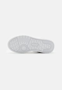 Fehér gumis sneaker talp, hexagonális mintával, kör alakú díszítésekkel és középen kidomborodó "LACOSTE" logóval.