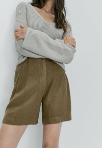 Gray knit sweater with a deep V-neck and loose sleeves, paired with brown linen shorts featuring a flat front and side pockets.
