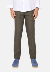 Olivově zelené lněné kalhoty s volným střihem, elastickými manžetami a bočními kapsami, doplněné modrými nazouvacími botami.