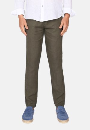 Pantalons en lin vert olive avec une coupe décontractée, dotés de poignets élastiques et de poches latérales, associés à des chaussures bleu slip-on.