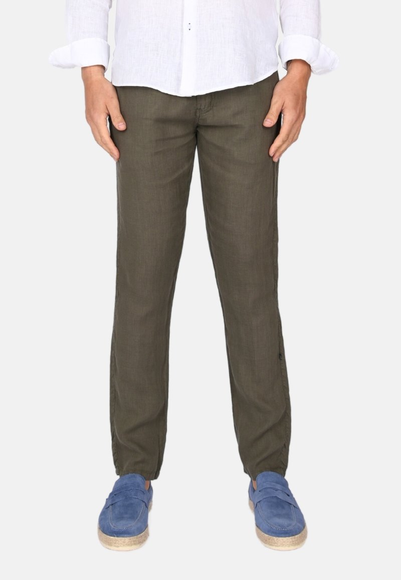 Olivově zelené lněné kalhoty s volným střihem, elastickými manžetami a bočními kapsami, doplněné modrými nazouvacími botami.