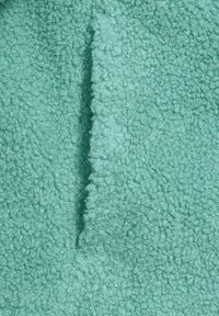 Tissu en polaire turquoise avec une surface douce et texturée présentant un design en boucle et duveteux. Le matériau semble léger et chaud.