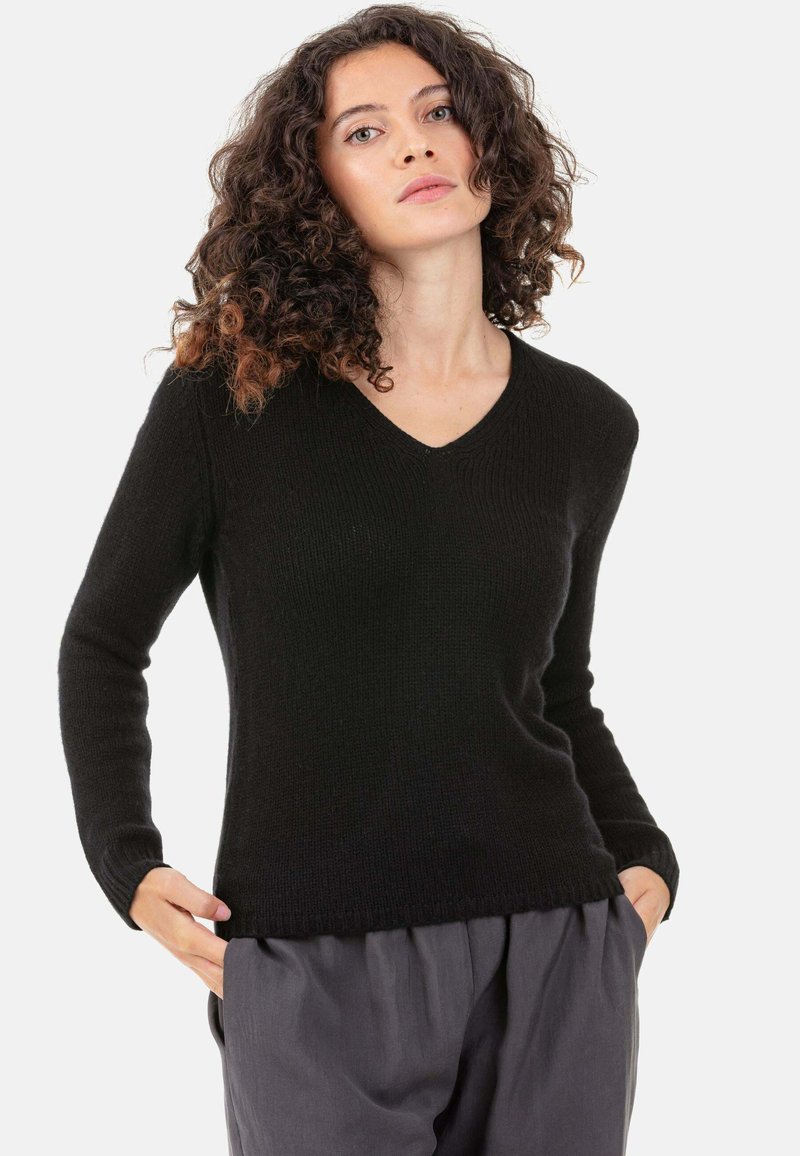 Pull noir à col en V en matière tricotée douce. Il comporte des manches longues, des poignets côtelés et une coupe décontractée avec une texture lisse.