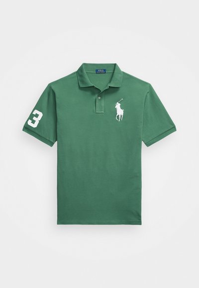 Žalias polo marškinėliai, pagaminti iš medvilnės, su baltu siuvinėtu logotipu ir numeriu 3 ant rankovės. Klasikinis apykaklės dizainas ir trumpomis rankovėmis.