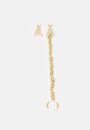 Oorbellen in goudkleurige bijenvorm, waarvan één met een korte ketting en een open cirkel detail op een witte achtergrond.