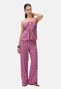 Completo a due pezzi composto da una parte superiore rosa senza spalline con un dettaglio a chiave e pantaloni ampi coordinati con un design simile.