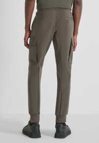 Olivgrüne Jogginghosen aus weichem Stoff, mit seitlichen Cargo-Taschen und schlankem Schnitt, mit gerippten Bündchen und glatter Textur.