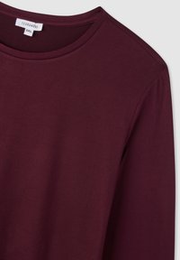 Camicia a maniche lunghe bordeaux in morbido cotone, con colletto rotondo e design senza cuciture sulle spalle. Presenta una vestibilità rilassata per garantire il massimo comfort.