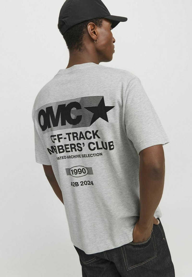 Camiseta de algodón gris con texto gráfico negro en negrita y motivo de estrella en la parte posterior, manga corta y un corte relajado.