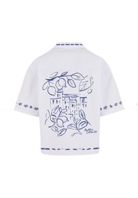 Korte mouwen witte shirt met een blauwe botanische print van citroenen en bladeren op de achterkant, met decoratieve stiksels op de mouwen en de zoom.