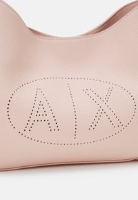 Rosa læderhåndtaske med tekstureret finish, der har perforerede bogstaver "A" og "X" inden i en oval form. Runde topkanter.