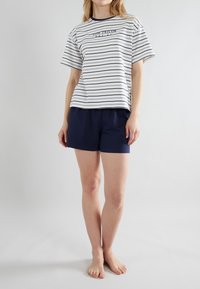 Gestreepte katoenen t-shirt in wit en marineblauw, met een ronde hals en korte mouwen, gecombineerd met marineblauwe shorts. Eenvoudig ontwerp, zachte textuur.