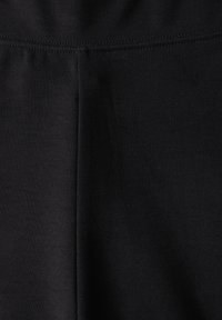 Zwarte stretchstof leggings met een gladde textuur, voorzien van een hoge tailleband en versterkte stiksels langs de naden.