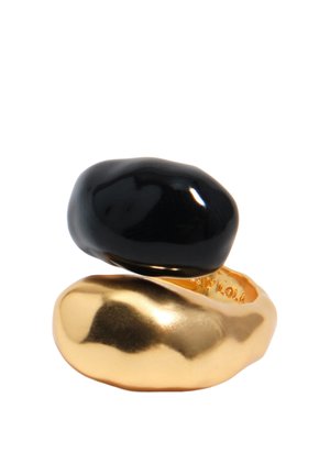 Gładkie, nieregularne pierścienie w kolorze złotym i czarnym ułożone warstwowo, o błyszczącym, polerowanym wykończeniu na białym tle.