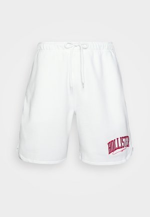 Weiße Baumwollshorts mit einem elastischen Bund, Kordelzug und rotem gesticktem "HOLLISTER" Logo am linken Bein. Glatte Textur.