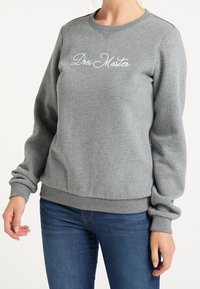 Grijze sweatshirt met ribgebreide manchetten en zoom, met daarop in het wit geborduurde tekst "Drei Master" op de borst. Zacht, gemêleerd stof.