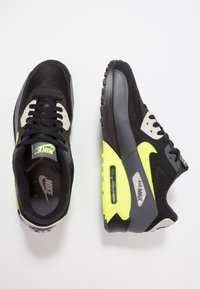 Černé a šedé tenisky Nike Air Max z kombinace síťoviny a syntetických materi álů s výrazným žlutým prvkem a viditelným vzduchovým polstrováním.