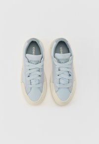Svijetloplave platnene tenisice s bijelim vezicama, gumene potplate i obloženi jezik. Sadrži "CONVERSE ALL STAR" oznaku na jeziku.