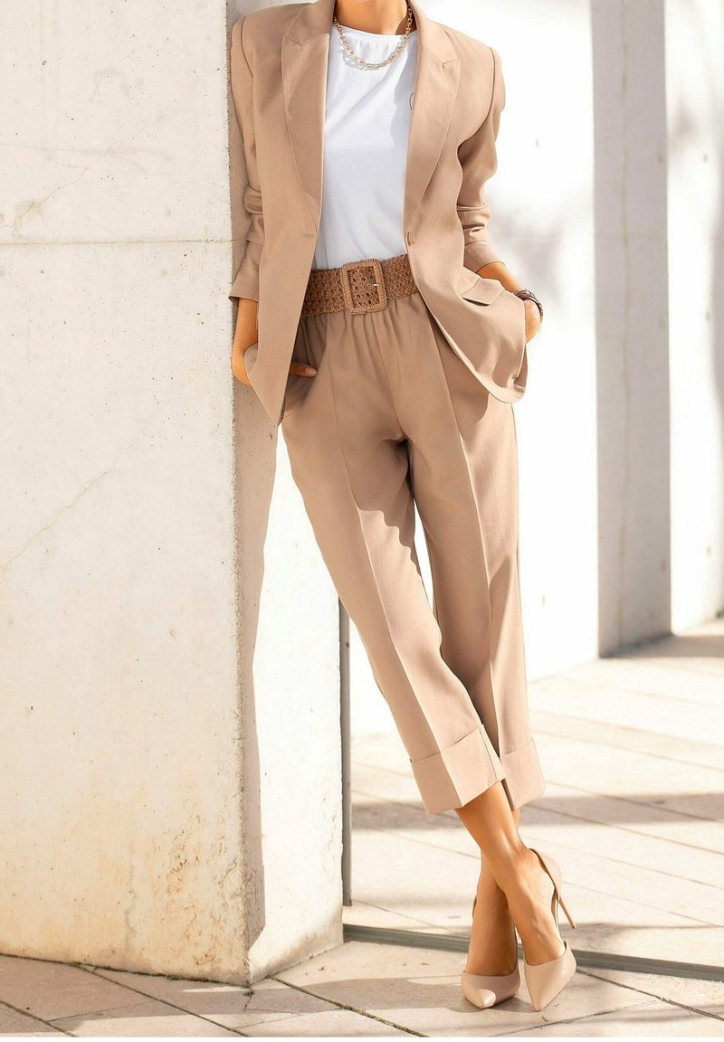 Beige sakový blazer a kalhoty s vysokým pasem, doplněné bílým topem a tkaným opaskem. Dokončeno béžovými vysoce podpatečnými botami.