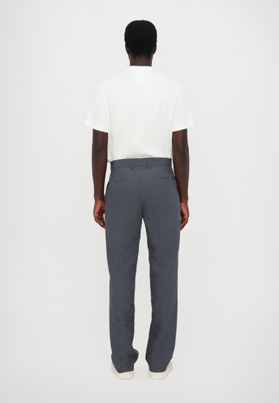 Pantalons gris à motif avec une coupe droite, dotés d'un devant plat, de passants de ceinture et de deux poches arrière, associés à un t-shirt blanc uni.