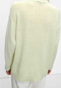 Pull tricoté vert clair avec une coupe ample, ourlet côtelé et tissu texturé, avec des épaules tombantes et un design décontracté.