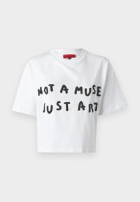 Vit kortärmad T-shirt med svart handskriven text "NOT A MUSE JUST ART" och en röd märkesetikett inuti kragen.