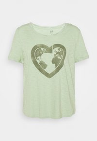 Camiseta de manga corta verde claro con una flecha en forma de corazón de color verde oscuro que rodea un mapa del mundo en la parte frontal.