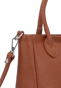 Braune Lederhandtasche mit genarbter Textur. Verfügt über einen abnehmbaren Schulterriemen und silberne Metallbeschläge. Abgerundete Griffe und kunstvolle Nähte.