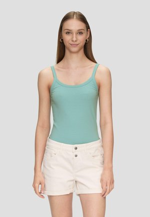 Mint green ribbed bodysuit with thin straps, paired with light beige rolled-up shorts featuring two front pockets and a button closure.