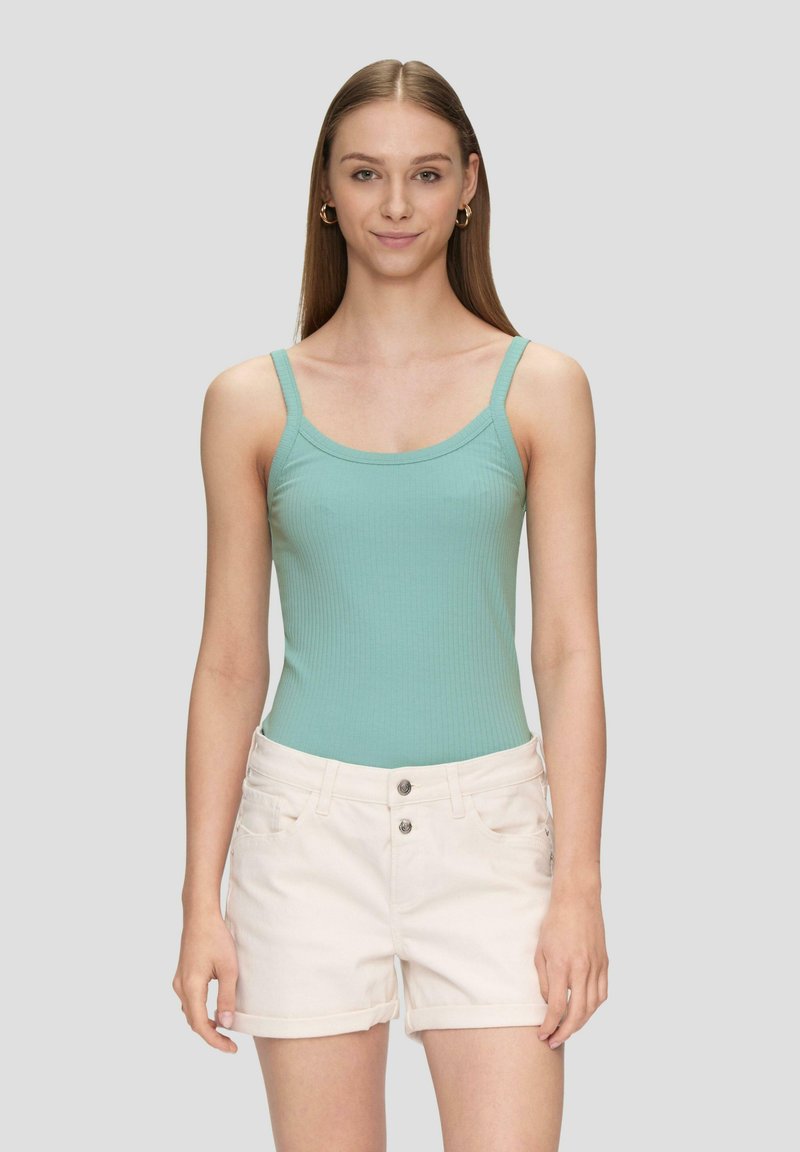 Minzgrüner, gerippter Bodysuit mit dünnen Trägern, kombiniert mit hellbeigen, hochgekrempelten Shorts mit zwei Vorderaschen und einem Knopfverschluss.