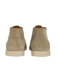 Botines de ante beige con una textura suave, que presentan una punta redondeada y una suela de goma ligera, ofreciendo un diseño minimalista.