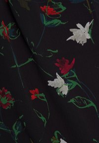 Tissu foncé avec un motif floral comprenant des fleurs rouges et blanches avec des tiges et des feuilles vertes disséminées à la surface.