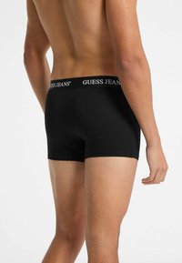 Boxer briefs nere da uomo realizzati in un tessuto morbido, caratterizzati da una cintura con logo con la scritta "GUESS JEANS" in bianco, design aderente e superficie liscia.