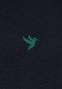 Tumesinine kampsun, millel on tekstureeritud kudum, mille vasakul küljel on roheline tikandiga kolibri disain.