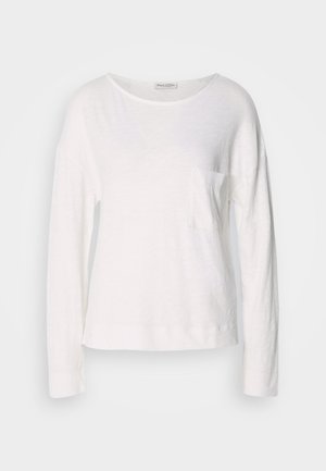 T-shirt à manches longues blanc en tissu léger et texturé, avec un col rond et une petite poche sur la poitrine. L'ourlet se situe au niveau des hanches.