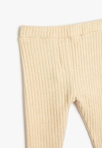 Pantalones de punto acanalado beige con cintura elástica, exhibidos en plano sobre un fondo blanco.