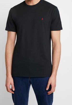 T-shirt en coton noir à manches courtes, col rond, avec un petit logo rouge sur la poitrine gauche. Texture douce et design ajusté standard.