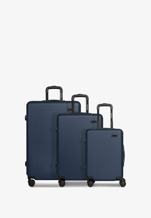 Tres maletas rígidas de color azul marino en tamaños pequeño, mediano y grande, cada una con asas telescópicas y cuatro ruedas giratorias.