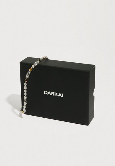 Czarna skrzynka DARKAI z bransoletką ozdobioną wielobarwnymi kamieniami na białym tle.