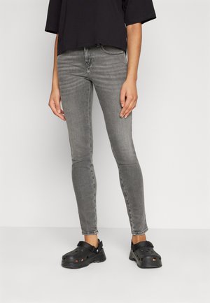 Šedé skinny džíny vyrobené z denimu, s středním pasem a přiléhavými nohavicemi. Doplněné černými dřeváky s perforovaným designem.