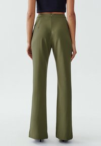 Weit ausgestellte, olivgrüne Hosen aus glattem Stoff, mit einem Reißverschluss auf der Rückseite und einem taillierten Bund für eine figurbetonte Silhouette.