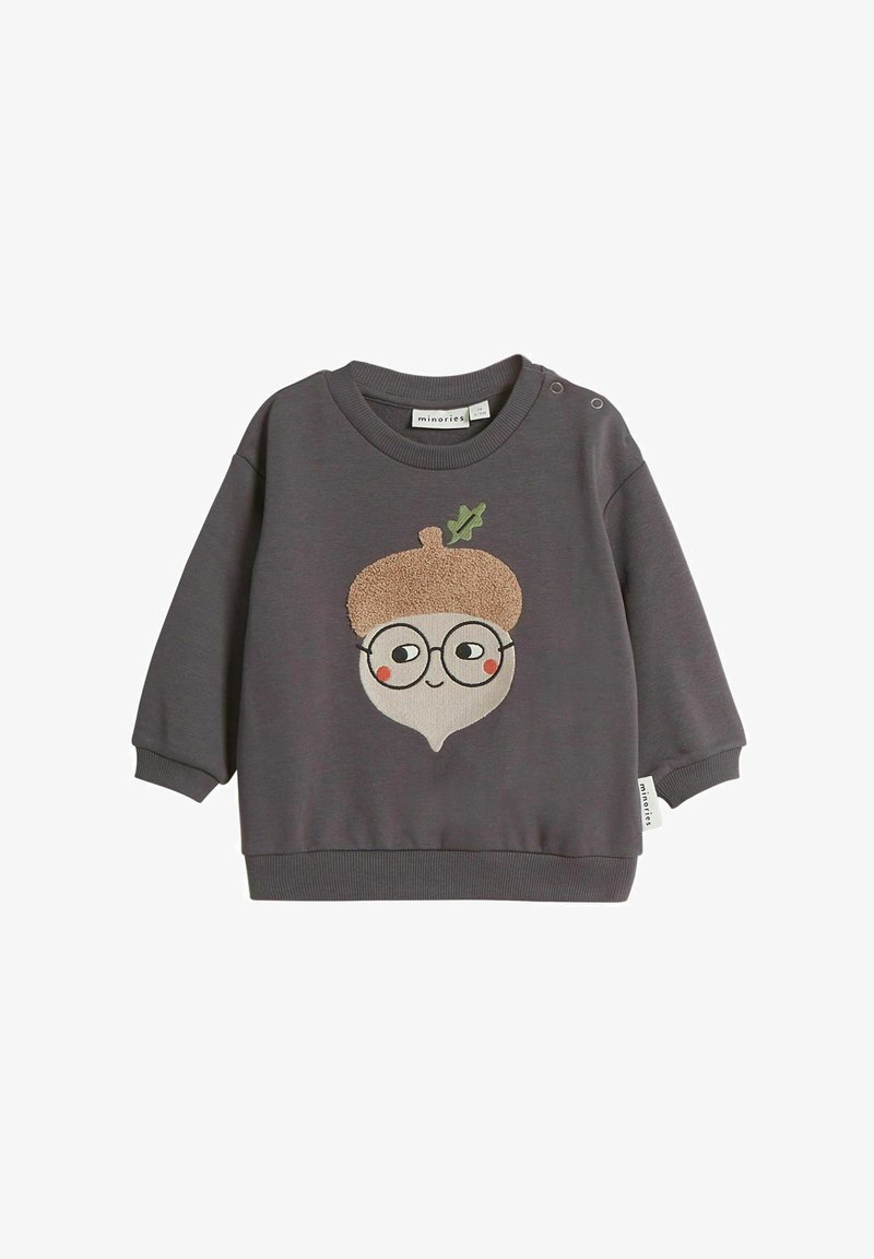 Harmaa huppari, jossa on tammenpähkinä-hahmo, jossa on teksturoitu ruskea hattu, pyöreät silmälasit ja ommeltuja yksityiskohtia. Napitus olkapäällä.