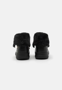 Mustat tekoturkisvuoriset nilkkurit, joissa on sileä nahkapinta, pyöreä kärki ja litteä kumipohja. Sivuilta vetoketjusomisteet.