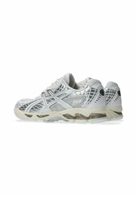Scarpe sportive bianche con tomaia in rete, dettagli riflettenti e suola ammortizzata con suola semitrasparente. Design performante.