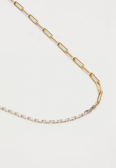 Δύο συνδεδεμένες αλυσίδες, μία χρυσή και μία ασημένια, διαθέτουν επιμηκυσμένους, ορθογώνιους συνδέσμους. Η χρυσή αλυσίδα βρίσκεται πάνω από την ασημένια αλυσίδα, προσφέροντας αντίθεση στο χρώμα.