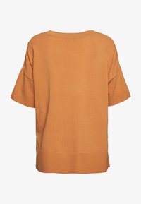 Krótki sweter z krótkim rękawem o luźnym kroju w stonowanym pomarańczowym odcieniu, wykonany z miękkiej dzianiny, z szerokim dekoltem i prążkowanym obszyciem.