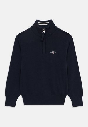 Jersey de punto azul marino con cuello de canalé, cremallera hasta la mitad, mangas largas y pequeño logo bordado en el pecho izquierdo.