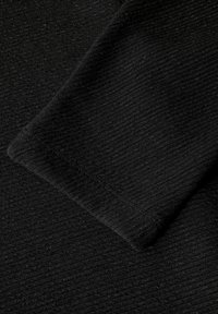 Zwarte stof met een gestructureerd, geribbeld patroon met een lichte glans. Randen zijn afgewerkt met een gladde zoom. Geen zichtbare versieringen.