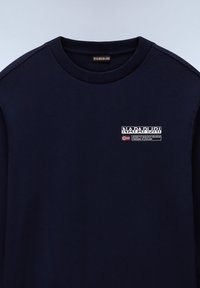 Marineblå sweatshirt lavet af blødt materiale, med rund hals, ribbede manchetter og et lille logo med tekst og flagdetalje.